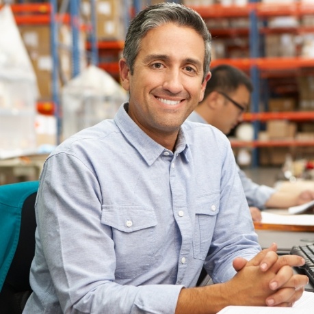 Smiling man in denim shirt sitting at desk